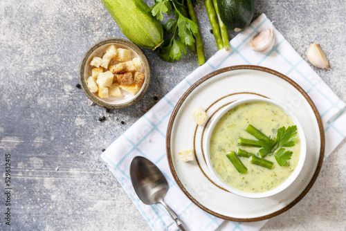 Healthy food. Vegan soup puree of green vegetables. Bowl of green bean and zucchini cream soup on a stone table. View from above.