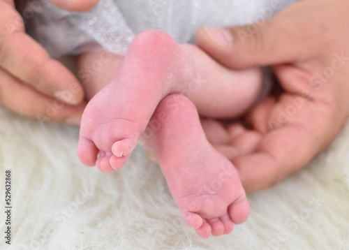feet of a newborn baby in male hands
