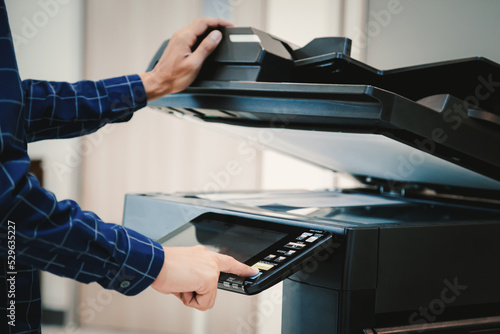 Copier printer  Close up hand office man press copy button on panel to using the copier or photocopier machine for scanning document printing a sheet paper.