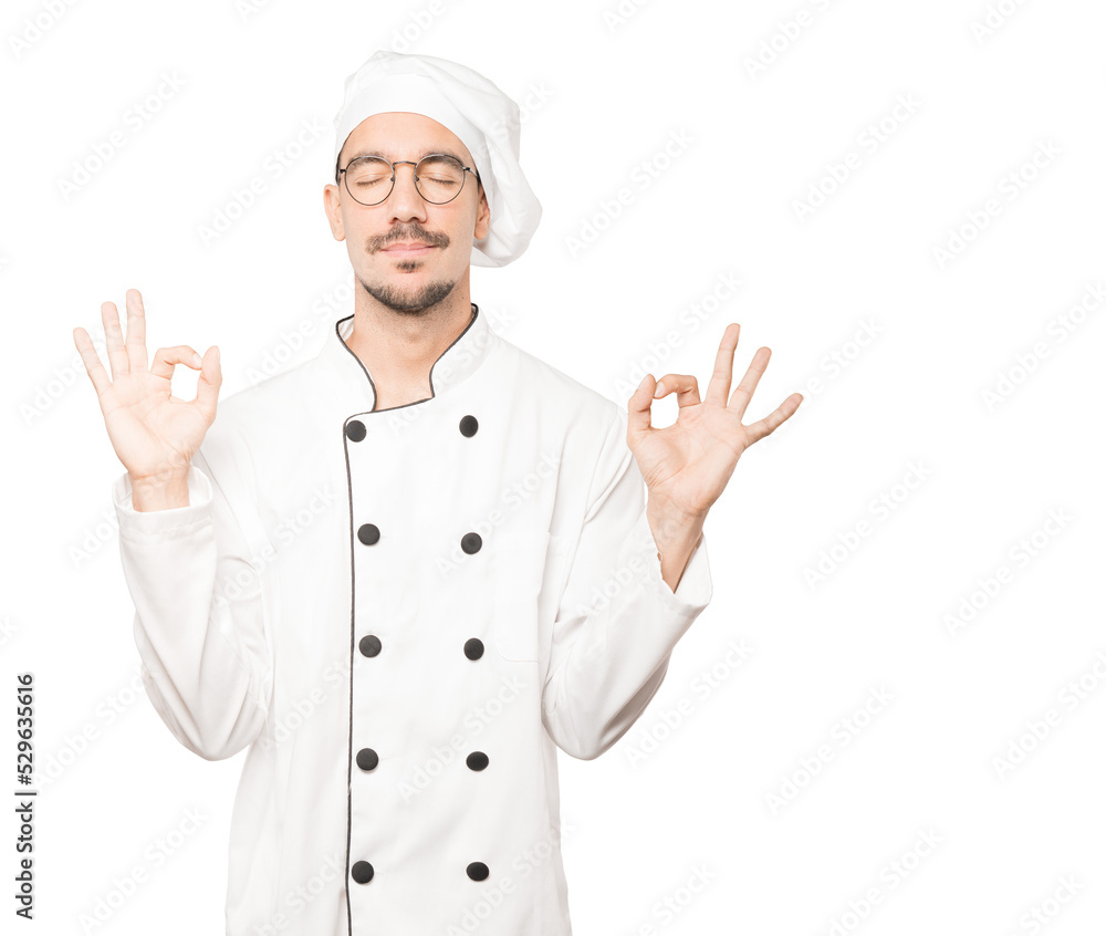 Happy young chef doing a gesture of meditation Happy young chef doing a gesture of meditation