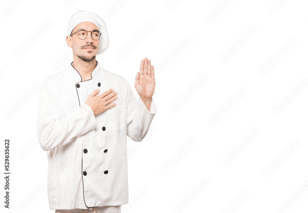 Serious young chef with a gesture of oath Serious young chef with a gesture of oath