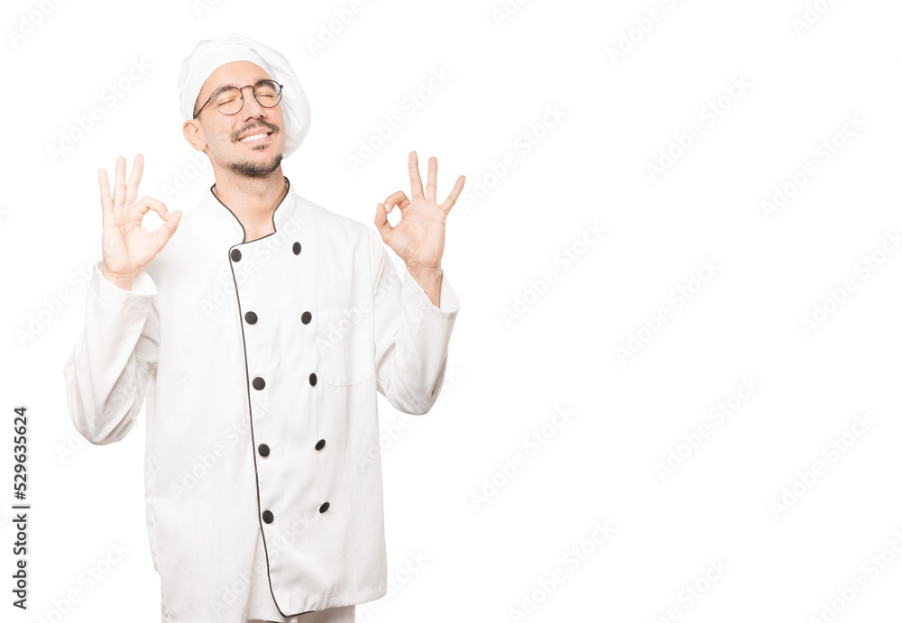 Happy young chef doing a gesture of meditation Happy young chef doing a gesture of meditation