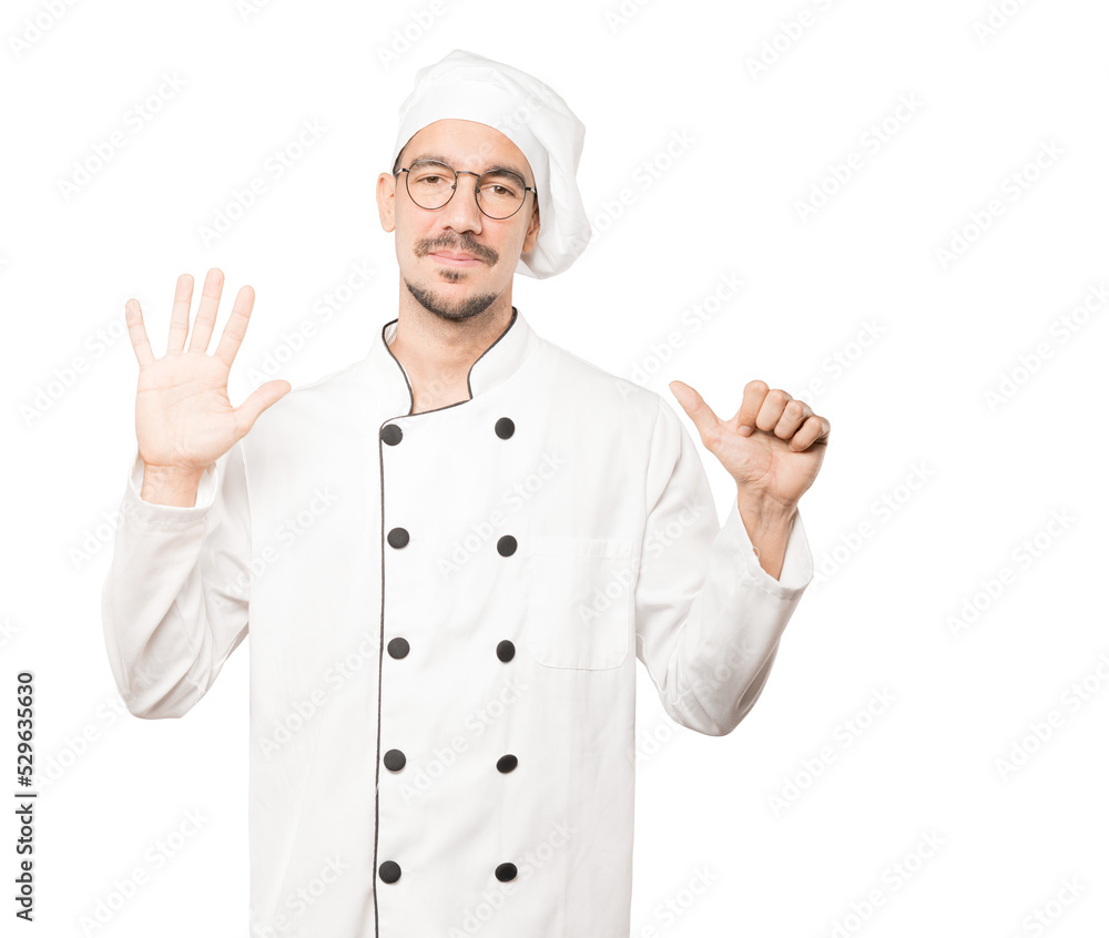 Happy young chef doing a number six gesture with his hands Happy young chef doing a number six gesture with his hands