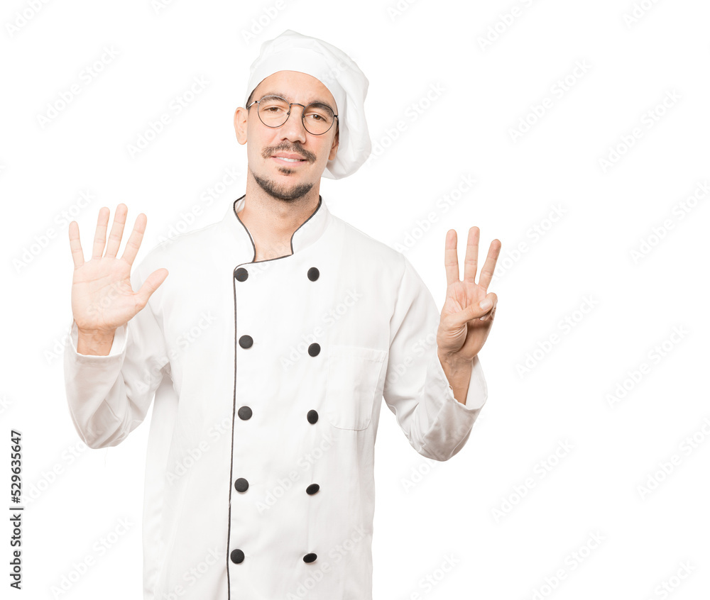 Happy young chef doing a number eight gesture with his hands Happy young chef doing a number eight gesture with his hands