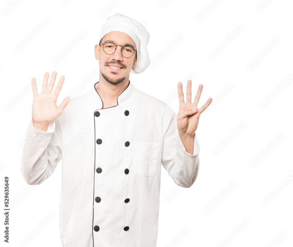 Happy young chef doing a number nine gesture with his hands Happy young chef doing a number nine gesture with his hands