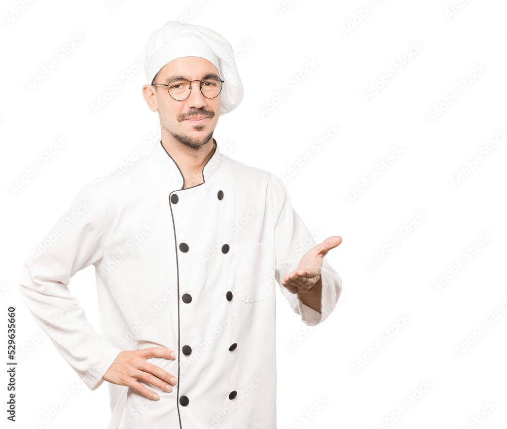 Happy young chef doing a gesture of welcome with his hand Happy young chef doing a gesture of welcome with his hand