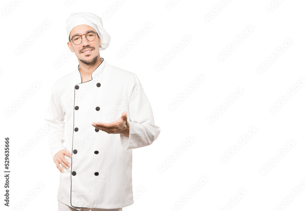 Happy young chef doing a gesture of welcome with his hand