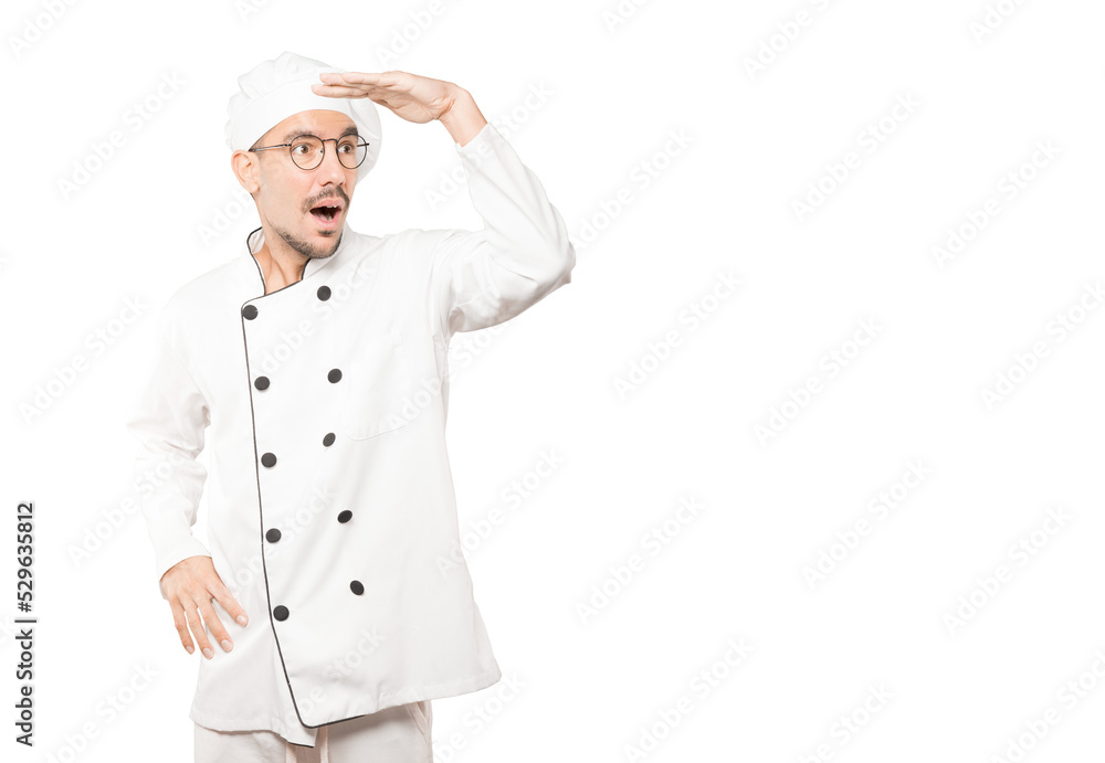 Astonished young chef with a gesture of looking away Astonished young chef with a gesture of looking away