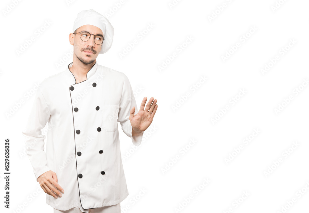 Doubtful young chef doing a gesture of keep calm Doubtful young chef doing a gesture of keep calm