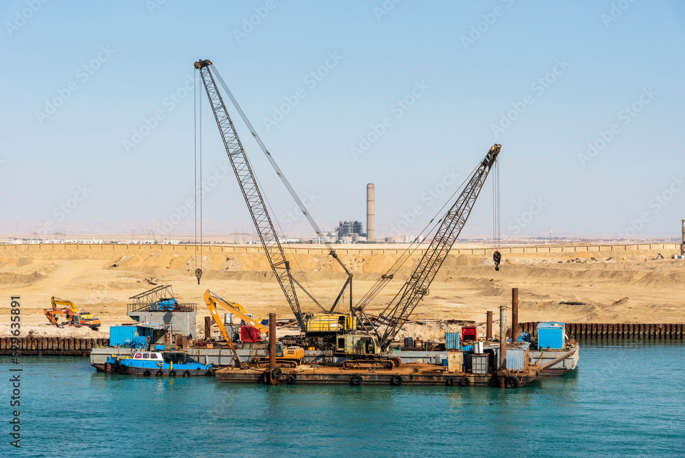 Floating cranes berthed at the bank of the Suez Canal, Egypt.