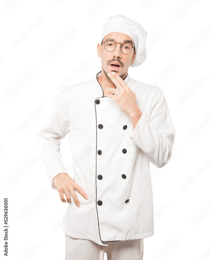 Surprised young chef making a gesture of doubt Surprised young chef making a gesture of doubt