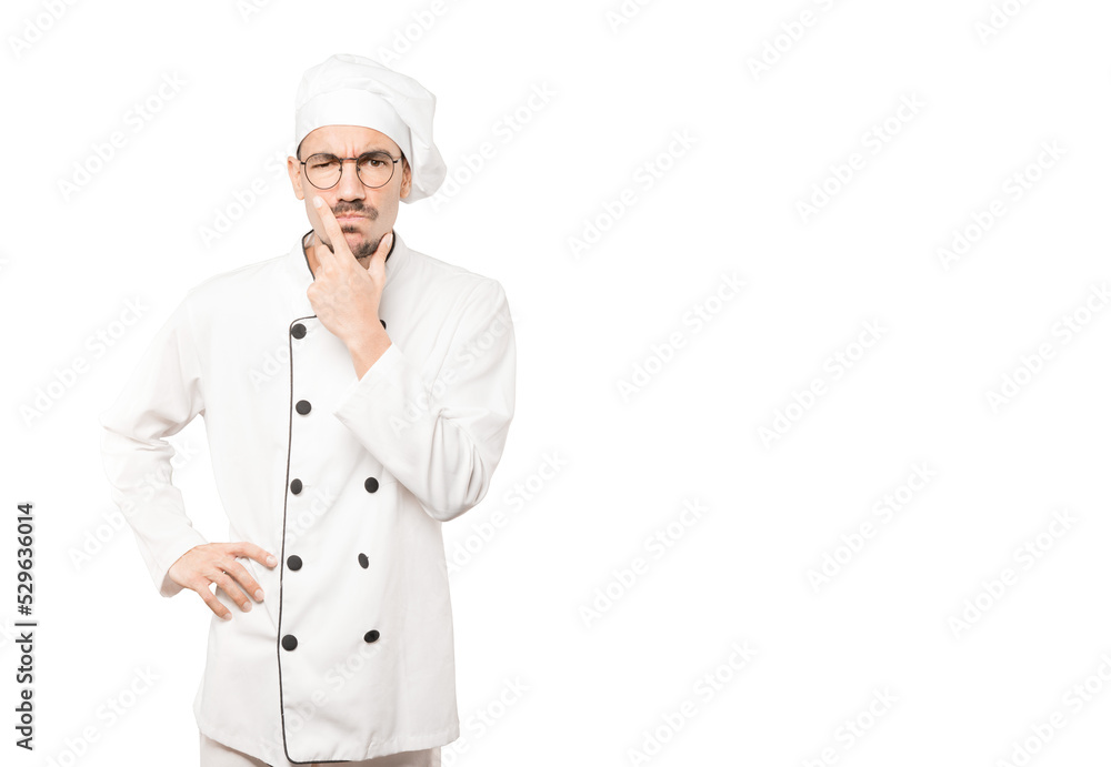 Concerned young chef making a gesture of doubt Concerned young chef making a gesture of doubt