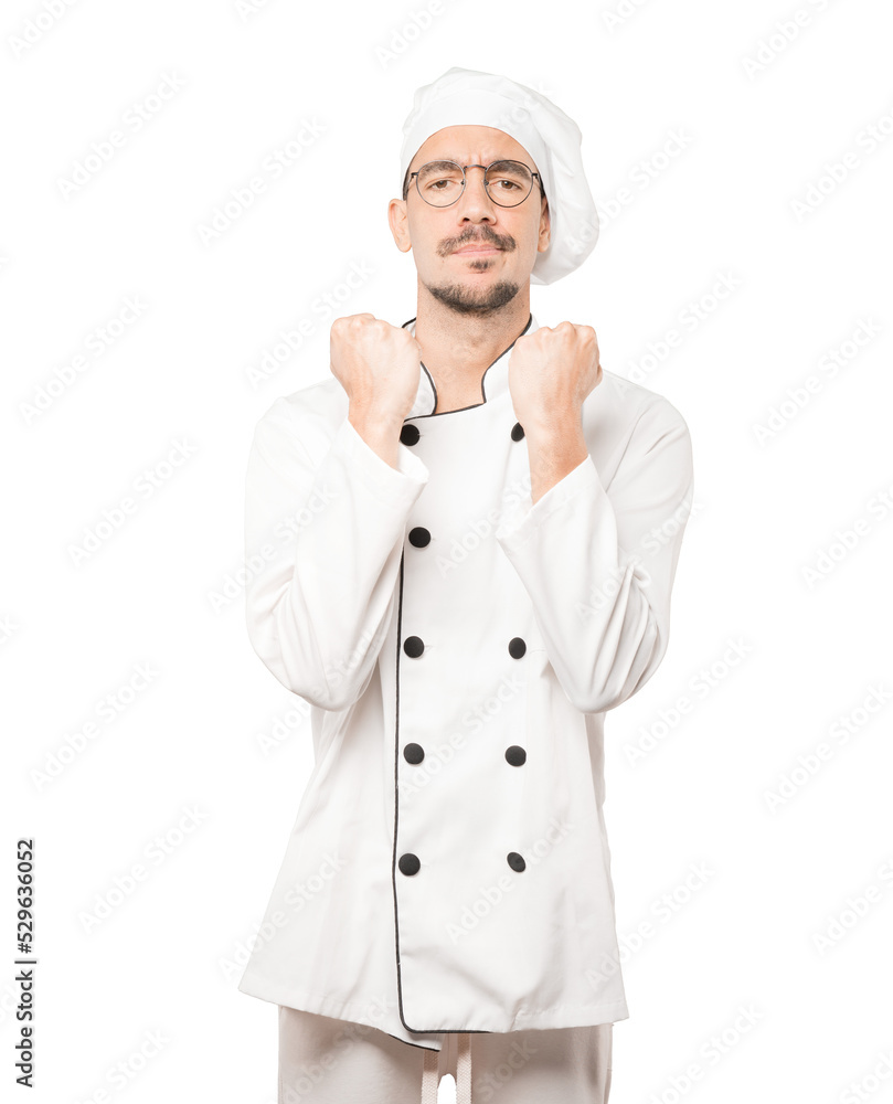 Serious young chef making a gesture of strength Serious young chef making a gesture of strength