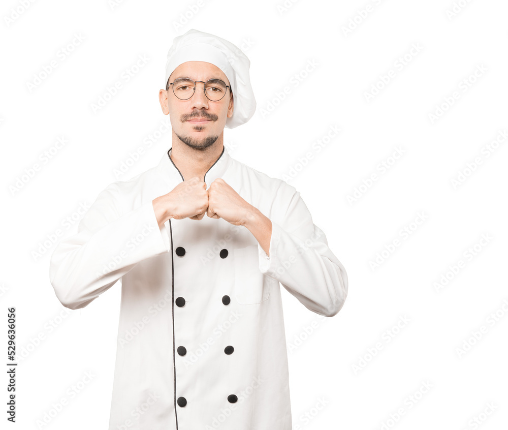 Serious young chef making a gesture of strength Serious young chef making a gesture of strength
