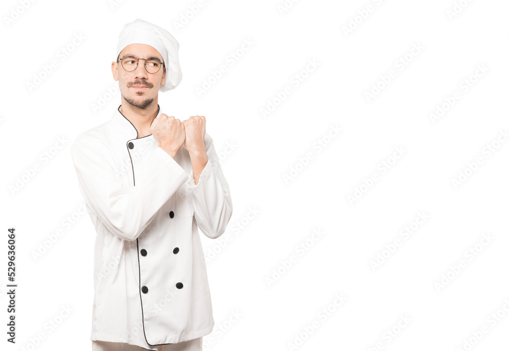 Serious young chef making a gesture of strength Serious young chef making a gesture of strength