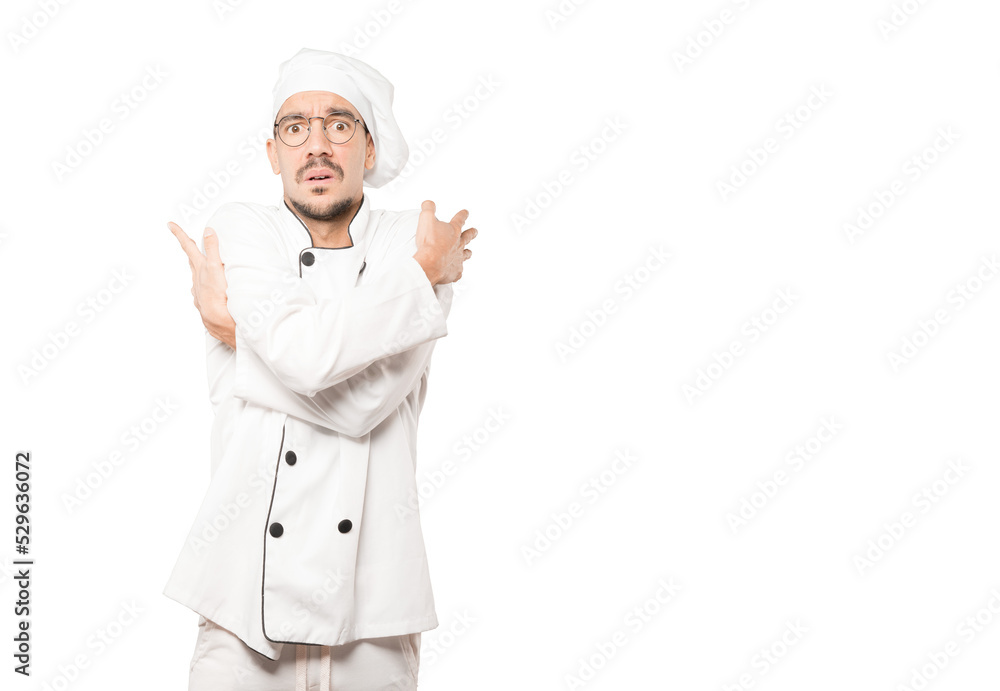 Concerned young chef making a gesture of being cold Concerned young chef making a gesture of being cold
