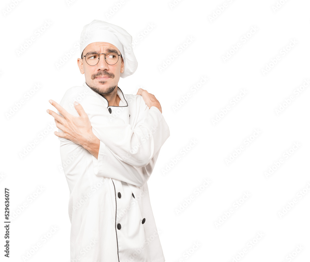 Concerned young chef making a gesture of being cold Concerned young chef making a gesture of being cold