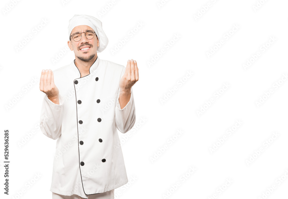 Confused young chef making an italian gesture of not understand Confused young chef making an italian gesture of not understand