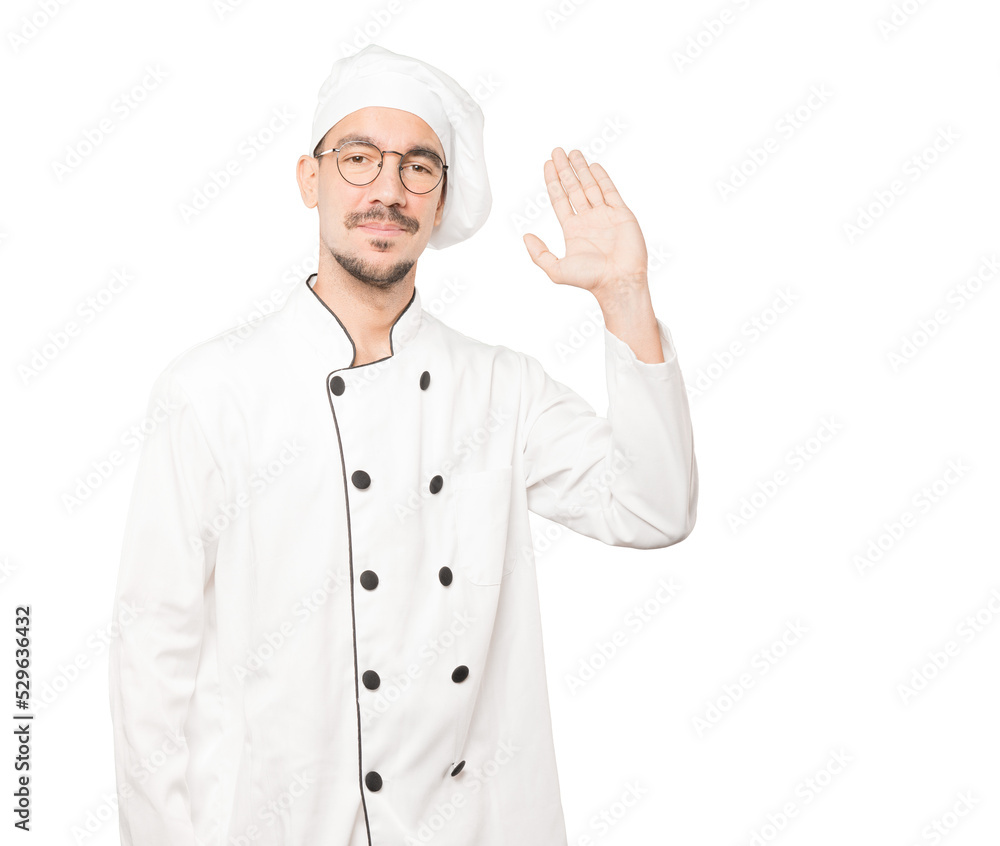 Young chef waving with his hand Young chef waving with his hand