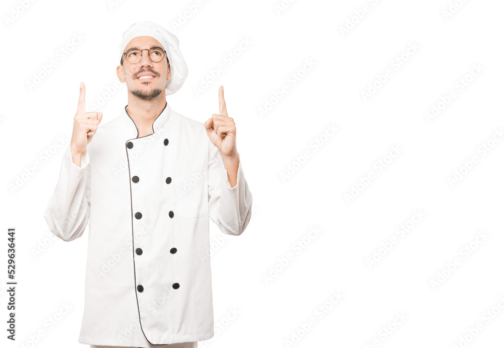 Happy young chef pointing up with his finger Happy young chef pointing up with his finger