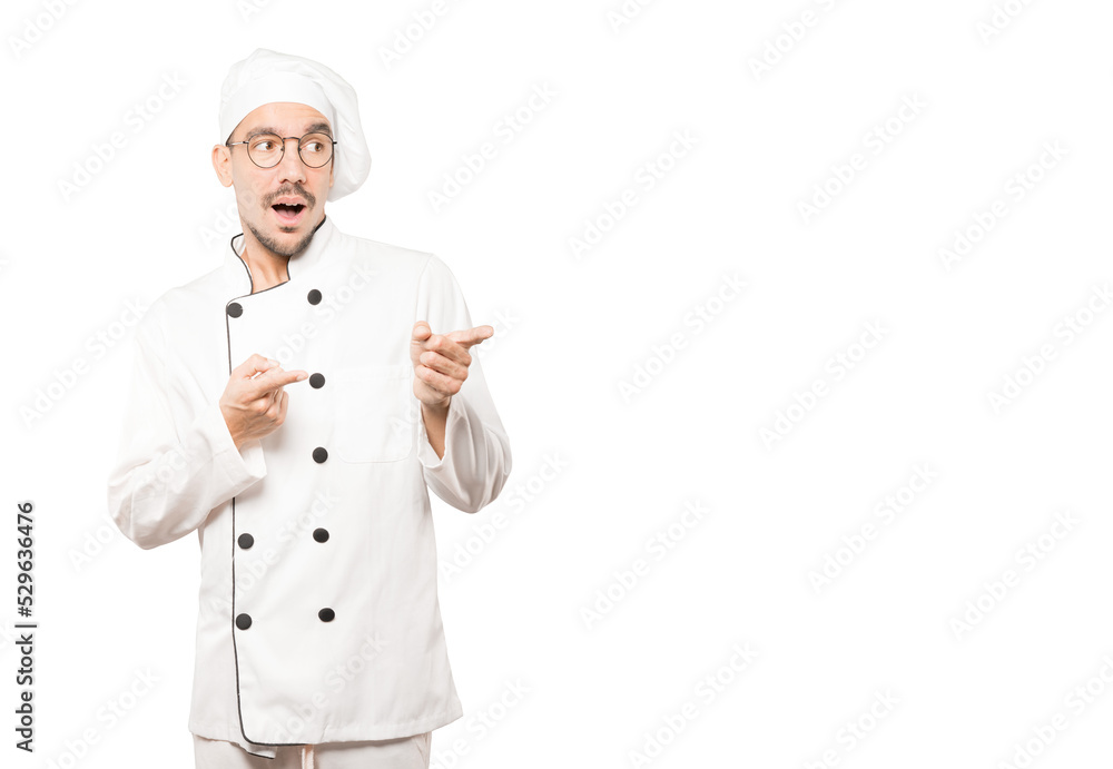Amazed young chef pointing at you with his finger Amazed young chef pointing at you with his finger