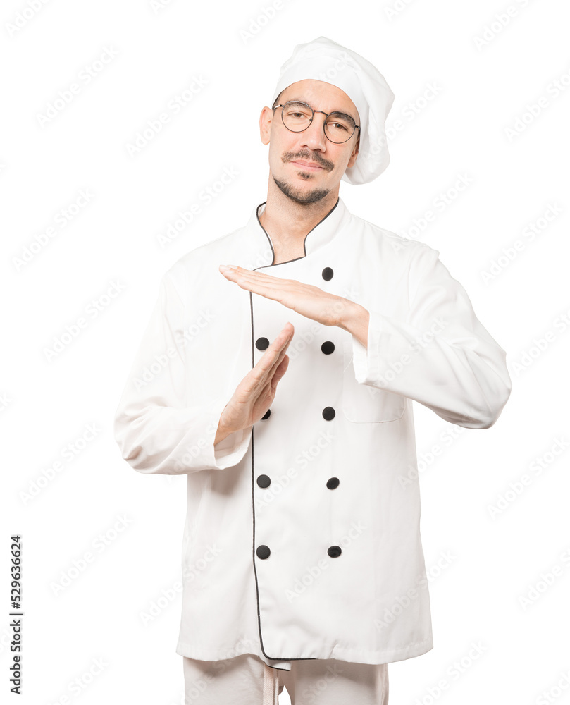 Stressed young chef making a time out gesture with his hands Stressed young chef making a time out gesture with his hands