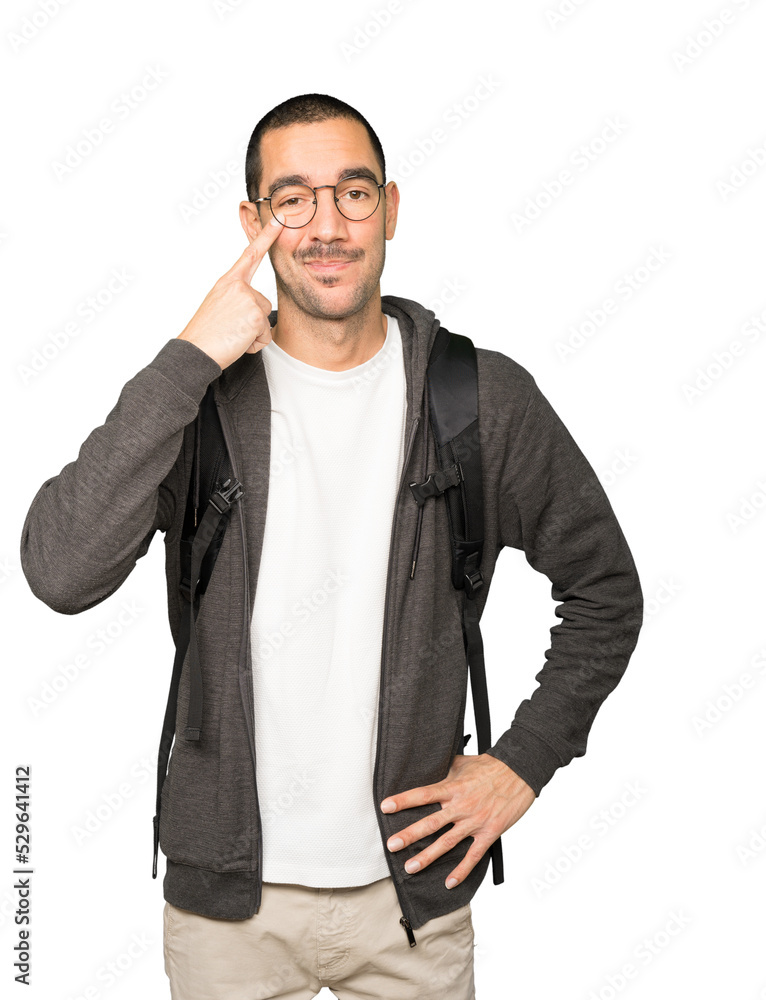 Hesitant student making a gesture of being careful with his hand pointing at his eye Hesitant student making a gesture of being careful with his hand pointing at his eye