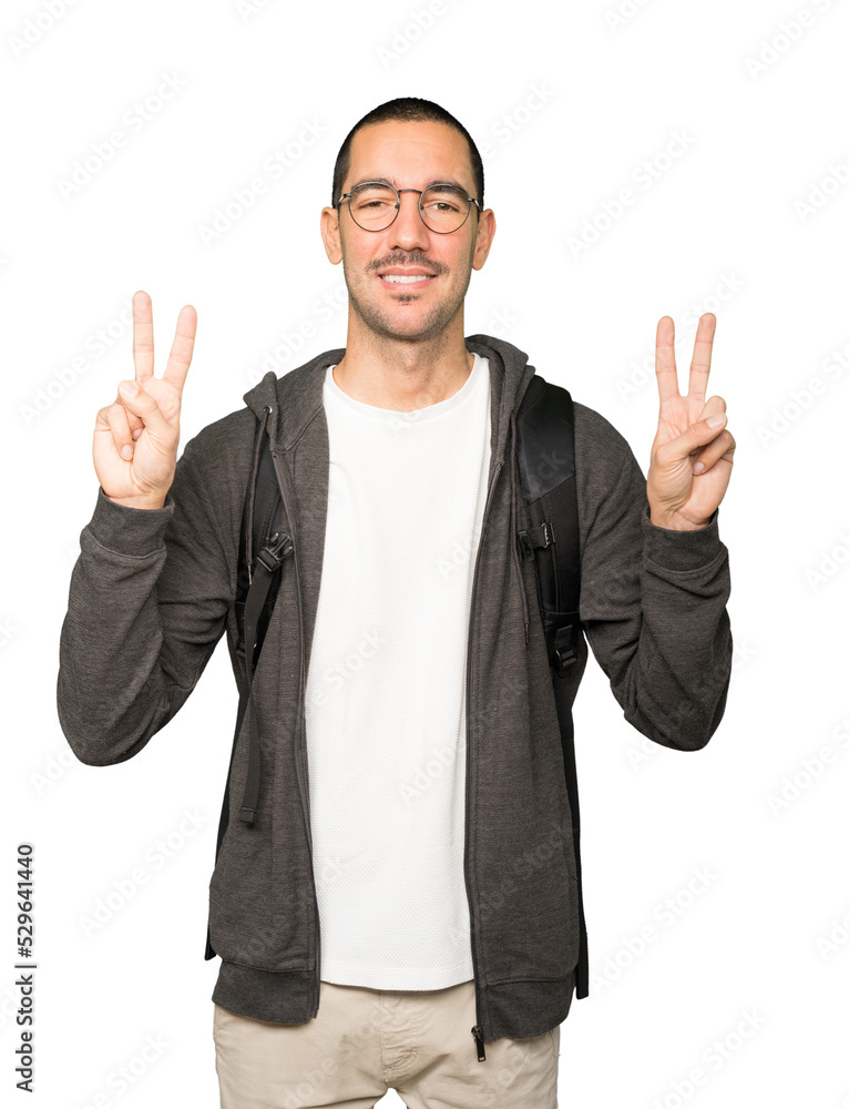 Happy student making a victory gesture with his fingers Happy student making a victory gesture with his fingers