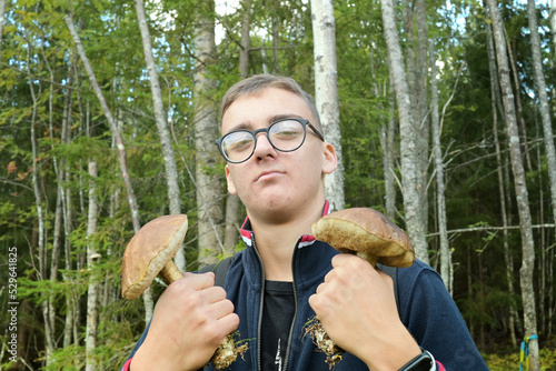 Boy teenager in glasses with mushrooms in the forest.