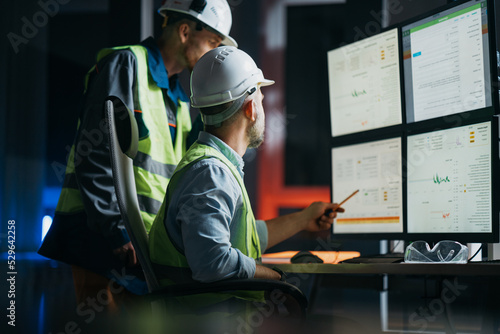 Group of operators control process on product line uses industry 4.0 and digital technology on modern factory. Two engineers follow assembly process uses SCADA system which AI technology and UI