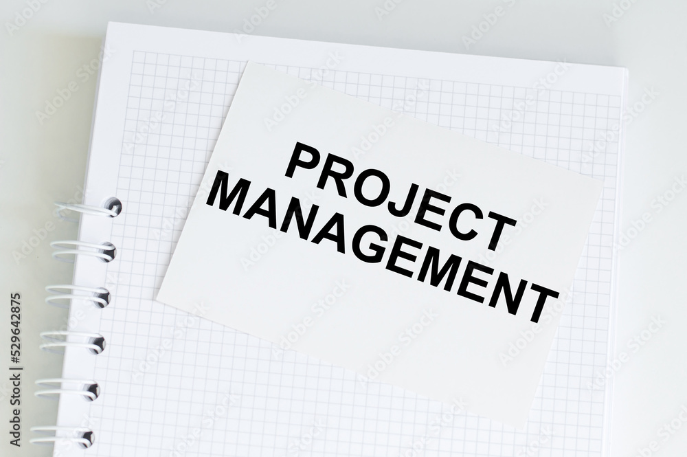 Obraz premium PROJECT MANAGER text on a card that lies on a notebook on a bright desk, a business concept