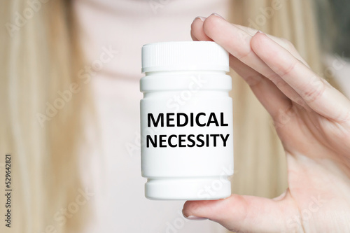 MEDICAL NECESSITY inscription on a white jar in a doctor's hand, medical concept