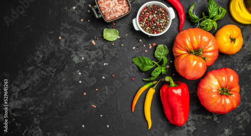Ingredients for cooking. vegetable with spices, bell pepper, chilli, basil, tomatoes and basil on a dark background. Long banner format. top view