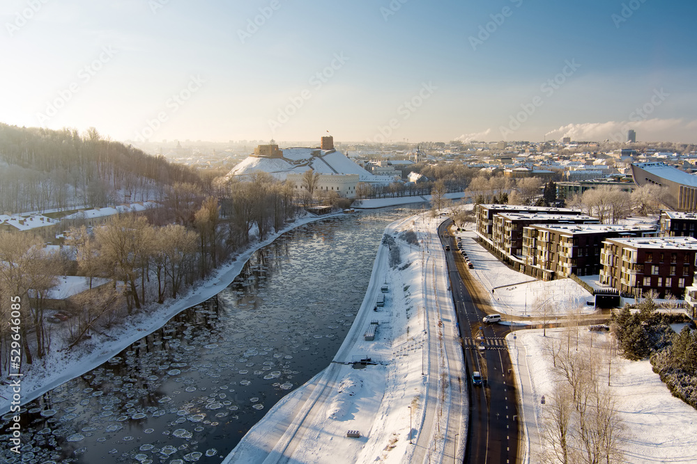 Naklejka premium Beautiful Vilnius city panorama in winter with snow covered houses, churches and streets. Aerial evening view. Winter city scenery in Lithuania.