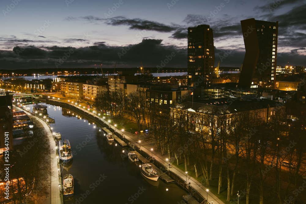 Aerial view of cityscape of Klaipeda at night. Yachts and boats docked along the embarkment of Dane river. Nightlife of Klaipeda, Lithuania.