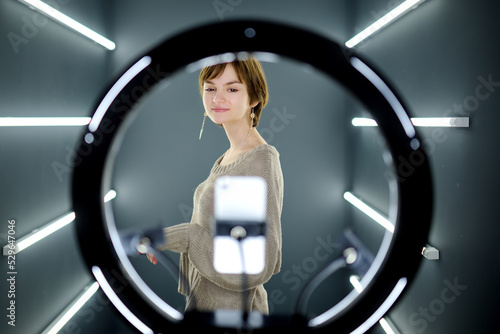 Beautiful teenage girl taking a selfie picture with mobile phone in light of the ring lamp.