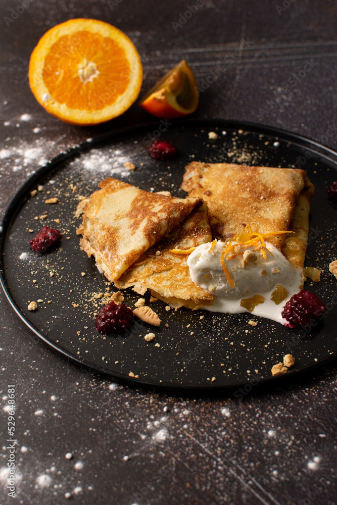 Crepes stuffed with orange marmalade with shortbread ice cream and powdered sugar
