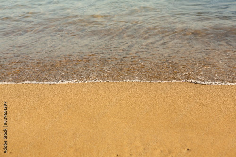 Background with golden sand on the coast of the island of Crete. Abstract surface with sand and clear sea water for text. Background with golden sand on the coast of the island of Crete. Abstract surface with sand and clear sea water for text.