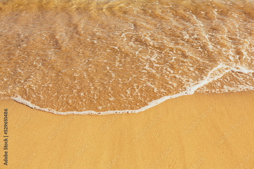 Background with golden sand on the coast of the island of Crete. Abstract surface with sand and clear sea water for text.