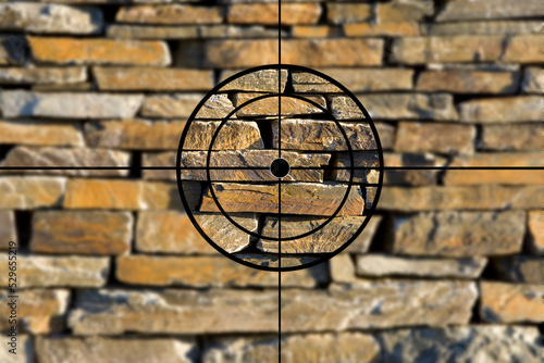 Fadenkreuz vor einer Steinwand