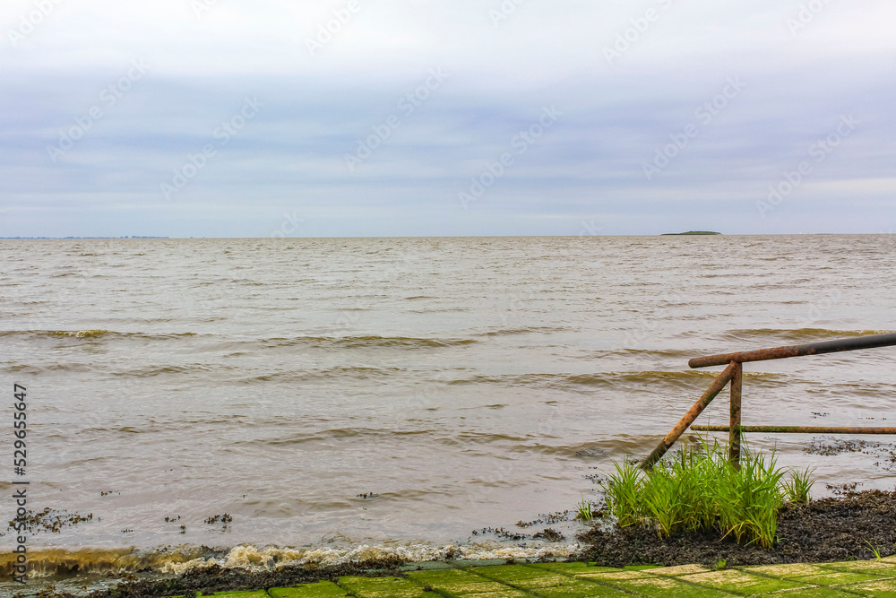 Dyke dike mudflat waves landscape North Sea coast Nordenham Germany.