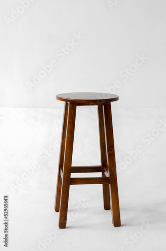Brown wooden stool with four legs on a white background