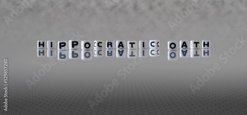hippocratic oath word or concept represented by black and white letter cubes on a grey horizon background stretching to infinity