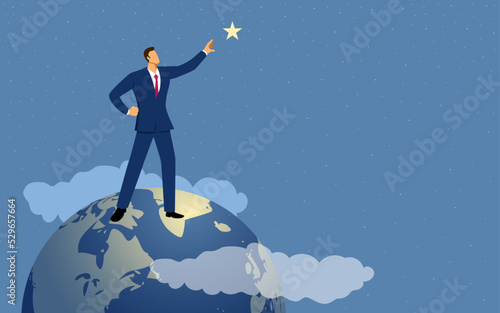 Businessman stands on globe and grabs a star