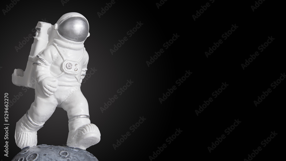 Plastic toy figure astronaut on a dark background with copy space. World Space Week 2022. Space and Sustainability. Close-up. Plastic toy figure astronaut on a dark background with copy space. World Space Week 2022. Space and Sustainability. Close-up.