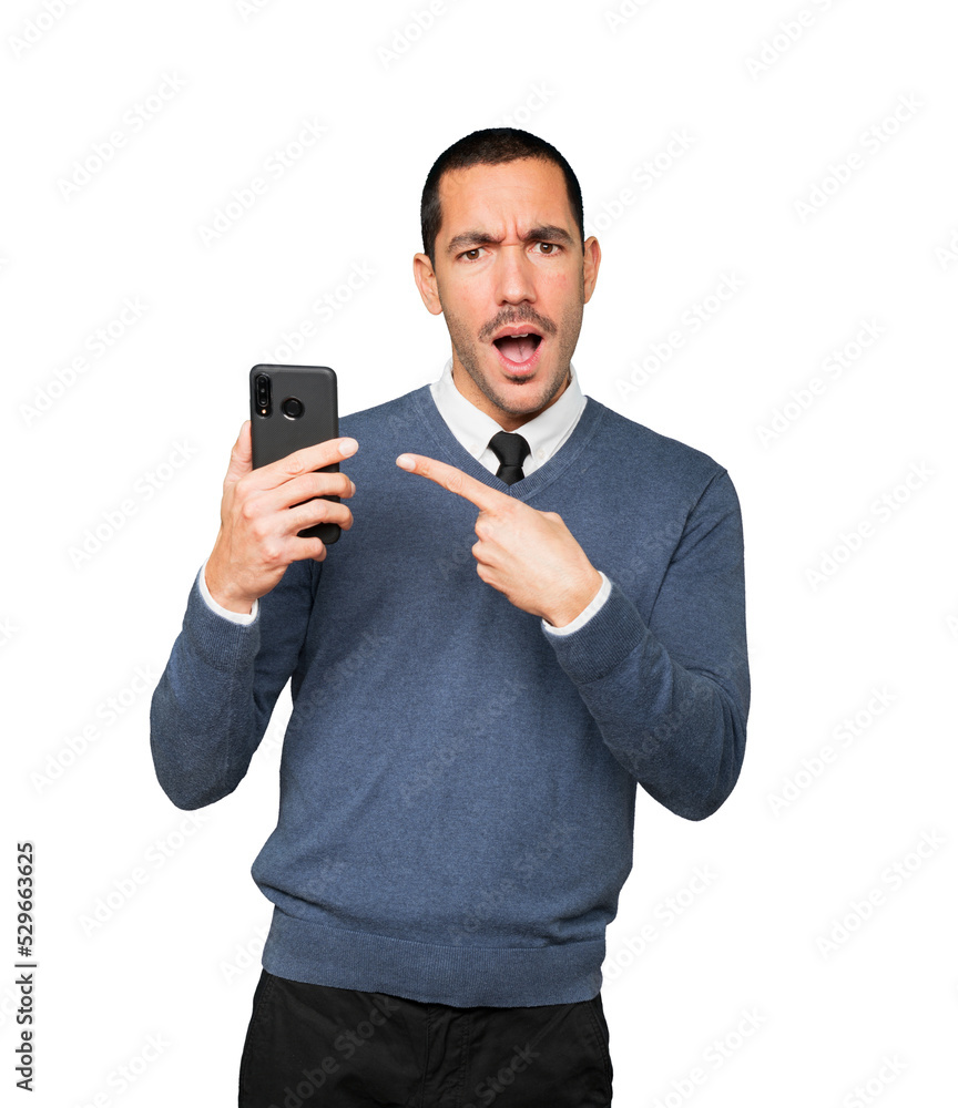 Surprised young man pointing and using his mobile phone Surprised young man pointing and using his mobile phone
