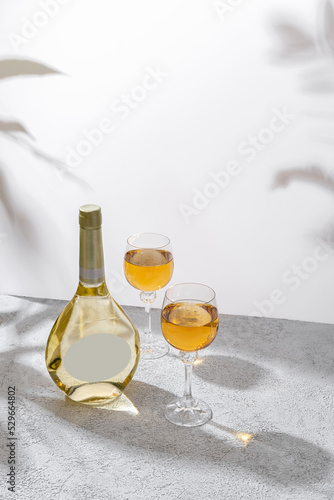 Glasses and bottle of white wine with blank label on light background. Wine making and wine degustation concept. Free space for your text