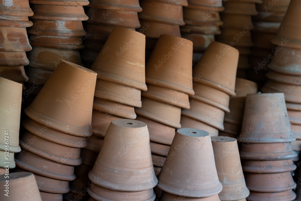 Closeup of stacks of old used weathered terra cotta flower pots in gardening shed. Empty vintage flowerpots. Closeup of stacks of old used weathered terra cotta flower pots in gardening shed. Empty vintage flowerpots.