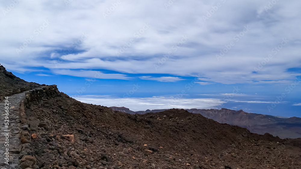 Well maintained hiking trail over volcanic desert terrain leading to summit of volcano Pico del Teide, Mount Teide National Park, Tenerife, Canary Islands, Spain, Europe. Solidified lava, ash, pumice Well maintained hiking trail over volcanic desert terrain leading to summit of volcano Pico del Teide, Mount Teide National Park, Tenerife, Canary Islands, Spain, Europe. Solidified lava, ash, pumice