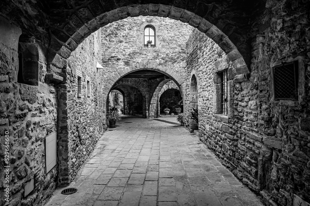 Passageways with stone arcade and medieval houses in a picturesque style and of great beauty, Monells, Girona, Catalonia.